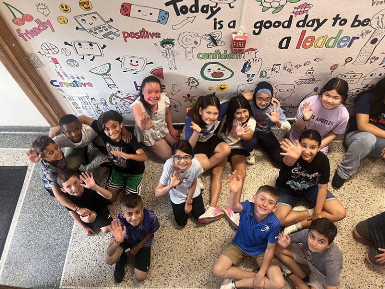 A group of students in front of a mural they are creating during the 2024 Summer Discovery Program.